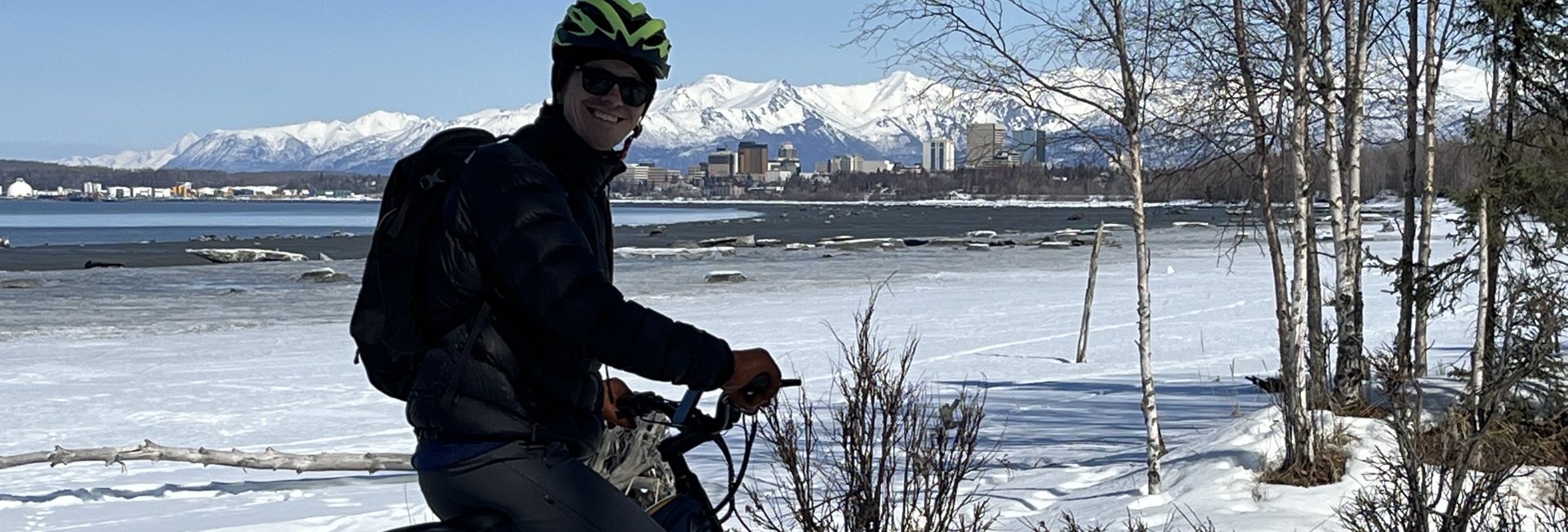 Man stopped on bike by ocean while biking on Anchorage Coastal Trail