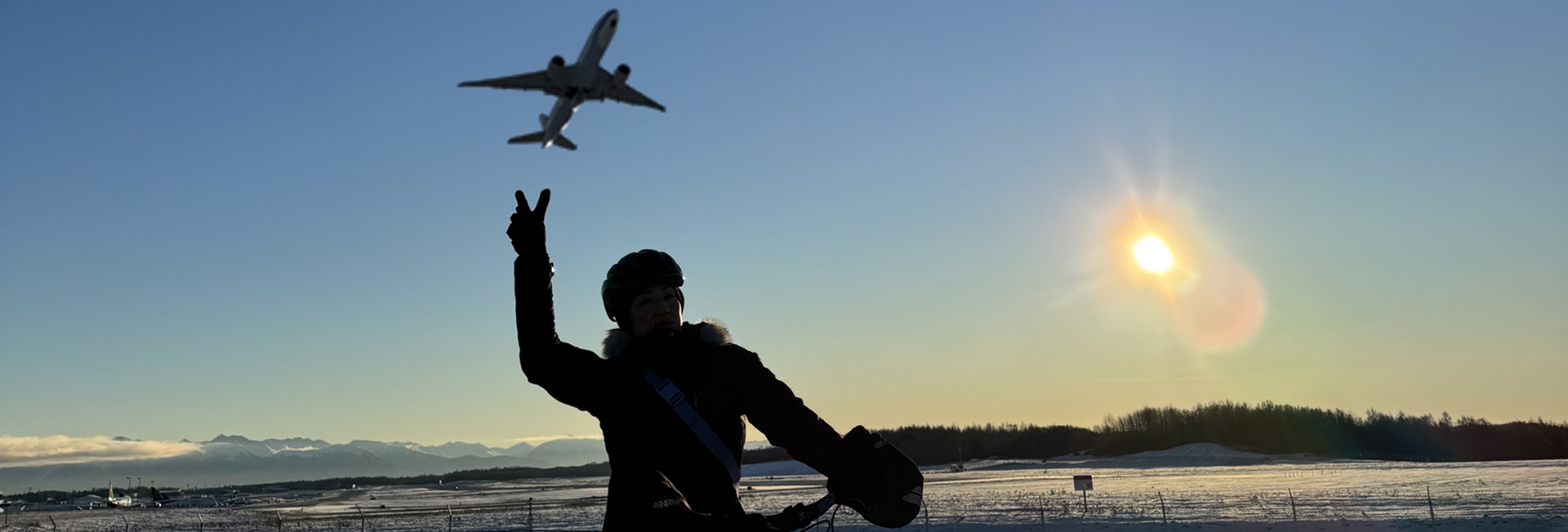 Woman on bike during sunrise and plane above